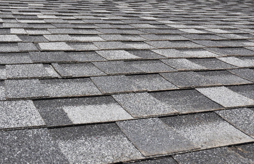 A detailed view of asphalt shingles installed on a residential roof, showing the layered pattern and textured surface typical of traditional roofing materials. The image captures the clean lines and uniform finish of a recently completed roof. This visual provides context for comparing roofing options and addresses the common question: is a metal roof cheaper than shingles when considering long-term value, durability, and installation costs.
